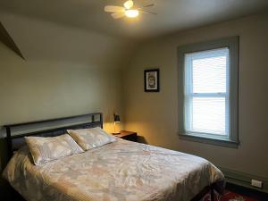 a bedroom with a bed with a ceiling fan and a window at Falls Retreat - Walk to the Falls, the Casino and all Downtown Restaurants - Across from the Aquarium in Niagara Falls