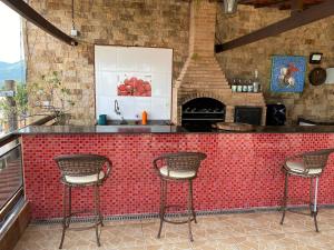 a kitchen with a red tiled counter with three bar stools at Cobertura luxuosa Marambaia in Barra de Guaratiba