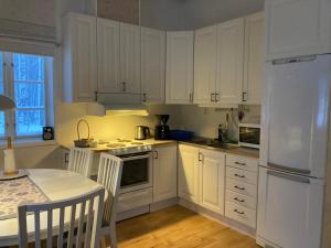 a white kitchen with white cabinets and a table at Huså Herrgård in Järpen