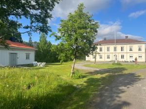 a white house with a tree in front of it at Huså Herrgård in Järpen