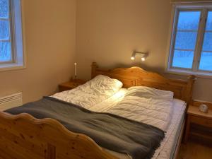 a bedroom with a large wooden bed with two windows at Huså Herrgård in Järpen