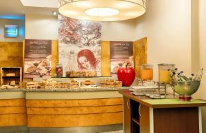 a restaurant with a counter with food on it at Leonardo Hotel Hannover Airport in Hannover