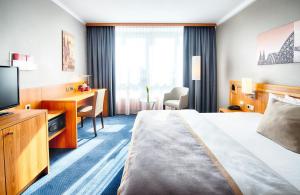 a hotel room with a bed and a desk and a television at Leonardo Hotel Köln Bonn Airport in Cologne