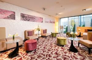 a waiting room with tables and chairs and a lobby at Leonardo Hotel Hannover Airport in Hannover