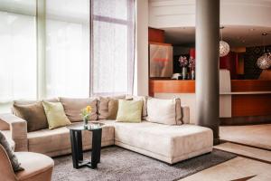 a living room with a couch and a table at Leonardo Hotel Aachen in Aachen +33 photos
