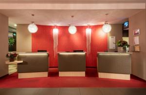 a lobby with a red wall with a row of seats at Leonardo Royal Hotel Köln - Am Stadtwald in Cologne