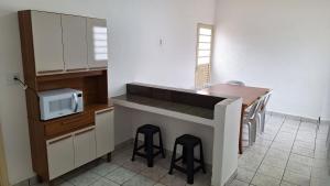 a kitchen with a sink and a counter with stools at Casa para 6 pessoas completa in Ribeirão Preto