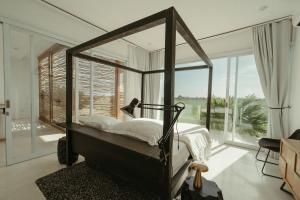 a bedroom with a canopy bed and a large window at The Iggy Villa 2BR in Cemagi +25 photos