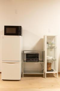 a white refrigerator with a microwave on top of it at one space 泊まれるコワーキングスペース in Kawatana