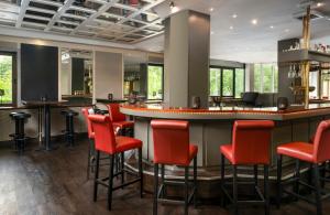 a bar with red bar stools in a restaurant at Leonardo Hotel Mönchengladbach in Mönchengladbach