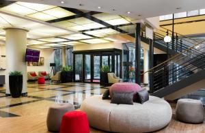 a large lobby with a chair and a staircase at Leonardo Hotel Munich Arabellapark in Munich +45 photos
