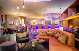a living room with a couch and a bar at Leonardo Hotel Wolfsburg City Center in Wolfsburg