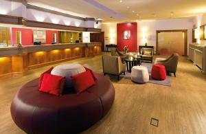 a living room with a large brown couch and chairs at Leonardo Hotel Heidelberg Walldorf in Walldorf