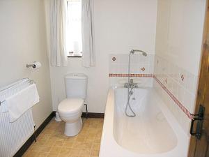 a bathroom with a toilet and a tub and a sink at Oak Tree Cottage in Kirkbymoorside +2 photos