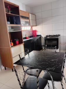 a kitchen with a black table and a stove at Casa completa in Marechal Deodoro