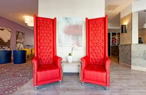 two red chairs sitting next to each other at Leonardo Hotel Munich City North in Munich +32 photos