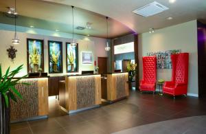 a lobby with a waiting room with red chairs at Leonardo Hotel Munich City East in Munich