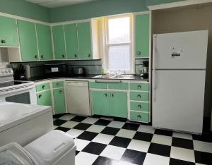 a kitchen with green cabinets and a black and white checkered floor at Falls Retreat - Walk to the Falls, the Casino and all Downtown Restaurants - Across from the Aquarium in Niagara Falls