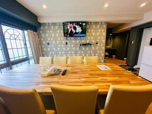a large wooden table with chairs and a television on a wall at Vacances Skytree Plaza in Tokyo