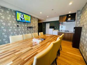 a dining room with a wooden table and a television on a wall at Vacances Skytree Plaza in Tokyo