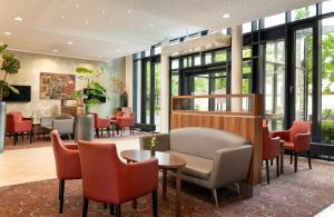 a waiting room with chairs and tables and windows at Leonardo Hotel Dresden Altstadt in Dresden