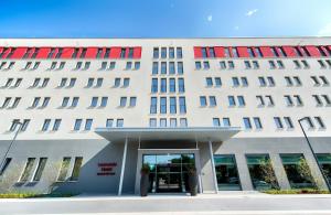 a large white building with red windows and a doorway at Leonardo Hotel Munich City East in Munich