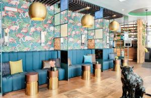 a lobby with a blue couch and pink flamingos wallpaper at NYX Hotel Munich by Leonardo Hotels in Munich