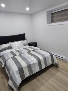 a bedroom with a bed with a checkered blanket at Cozy 1-Bedroom Private Basement Suite in Winnipeg with separate entrance in Winnipeg
