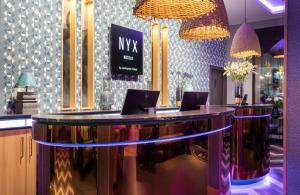 a bar in a salon with two laptops on the counter at NYX Hotel Bilbao by Leonardo Hotels in Bilbao