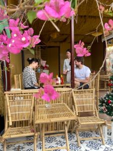 a group of people sitting at a restaurant with pink flowers at Pristine nature - Romantic - Green trees and lakes in Vũ Lâm