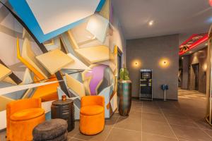 a lobby with orange chairs and a colorful wall at NYX Hotel Hamburg by Leonardo Hotels in Hamburg