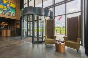a lobby with two chairs and a glass elevator at Leonardo Hotel Vinkeveen Amsterdam in Vinkeveen +70 photos