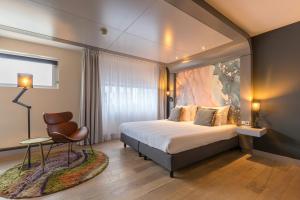 a hotel room with a bed and a chair at Leonardo Hotel Almere City Center in Almere