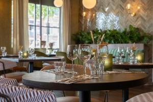 a table with wine glasses on it in a restaurant at Leonardo Hotel Breda City Center in Breda
