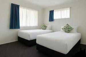 two beds in a hotel room with blue curtains at Pure Motel in Rotorua +25 photos