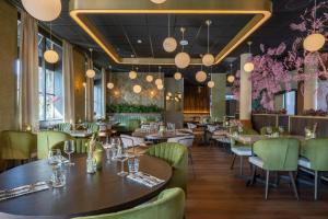a restaurant with wooden tables and green chairs at Leonardo Hotel Breda City Center in Breda