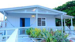 a white cottage with a porch and some plants at Comoda casa en segunda planta in Coamo