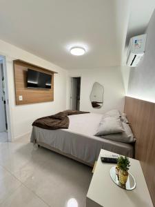 a bedroom with a bed with a tv and a table at Edifício Catamara in Vila Velha