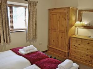 a bedroom with a bed and a dresser with two towels at Oak Tree Cottage in Kirkbymoorside
