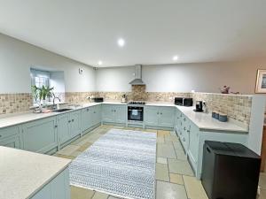 a large kitchen with blue cabinets and a rug at John Wesley Cottage in Tantobie