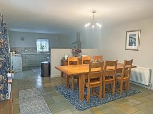 a kitchen and dining room with a wooden table and chairs at John Wesley Cottage in Tantobie