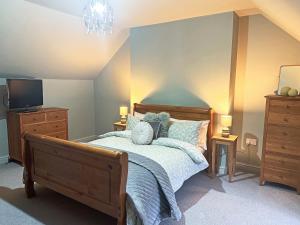 a bedroom with a bed with a dresser and a tv at John Wesley Cottage in Tantobie