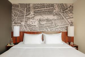 a bed with two pillows and a map on the wall at Leonardo Hotel Den Haag Babylon in The Hague +23 photos