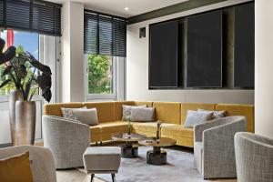 a living room with a yellow couch and chairs at Leonardo Hotel Mainz in Mainz +72 photos