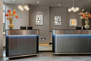 a lobby with two benches and a counter with flowers at Leonardo Hotel Mainz in Mainz