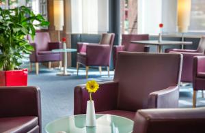 a vase with a yellow flower sitting on a table at Hotel Freiburg City Center by Leonardo Hotels in Freiburg im Breisgau