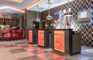 a bar in a restaurant with red lights at Leonardo Hotel Dortmund in Dortmund