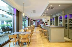 a restaurant with tables and chairs and a bar at Leonardo Hotel Budapest in Budapest