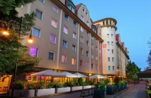 a hotel with tables and umbrellas in front of a building at Leonardo Hotel Budapest in Budapest +33 photos