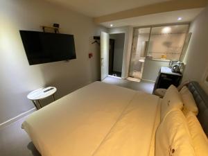 a bedroom with a large white bed and a flat screen tv at IDEA Hotel in Busan